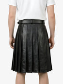 Black pleated leather skirt worn by a person on a white background