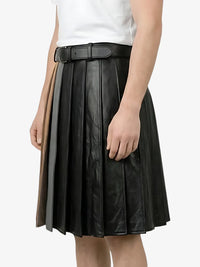 Black pleated leather skirt worn by a person on a white background