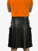Person wearing an orange shirt and black pleated leather skirt on a white background
