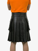 Person wearing an orange shirt and black pleated leather skirt on a white background