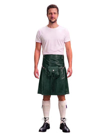 A man modeling a dark green leather kilt with a matching belt and pouch, paired with a white t-shirt, cream knee-high socks, and black lace-up shoes, against a plain white background.