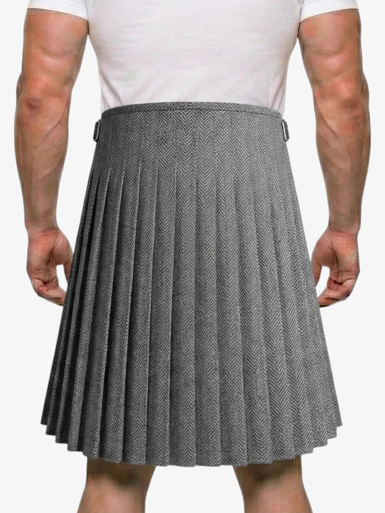 Person wearing a gray pleated kilt on a white background