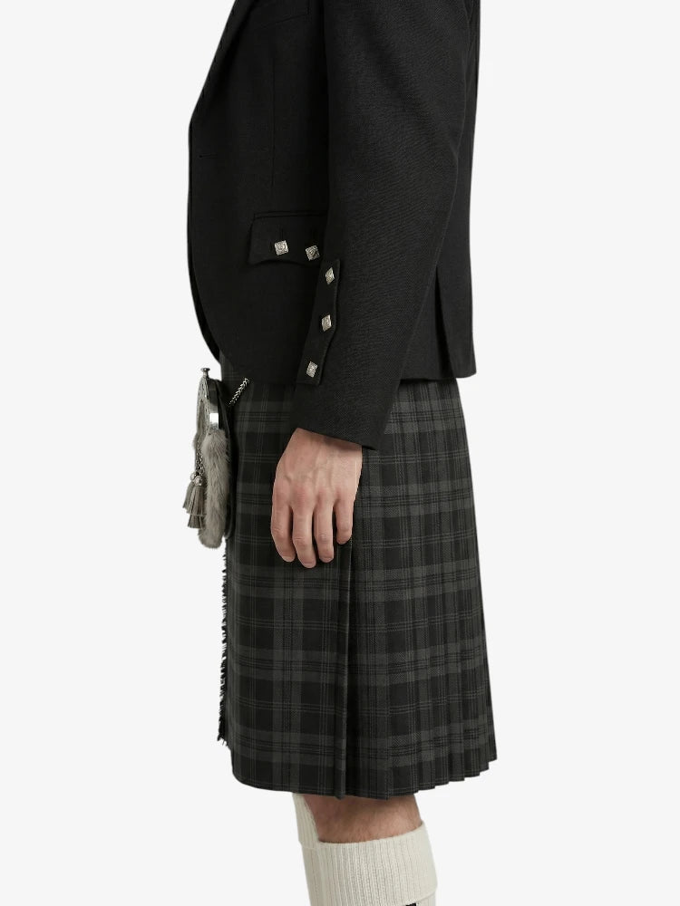 Person wearing a black blazer and plaid kilt on a white background
