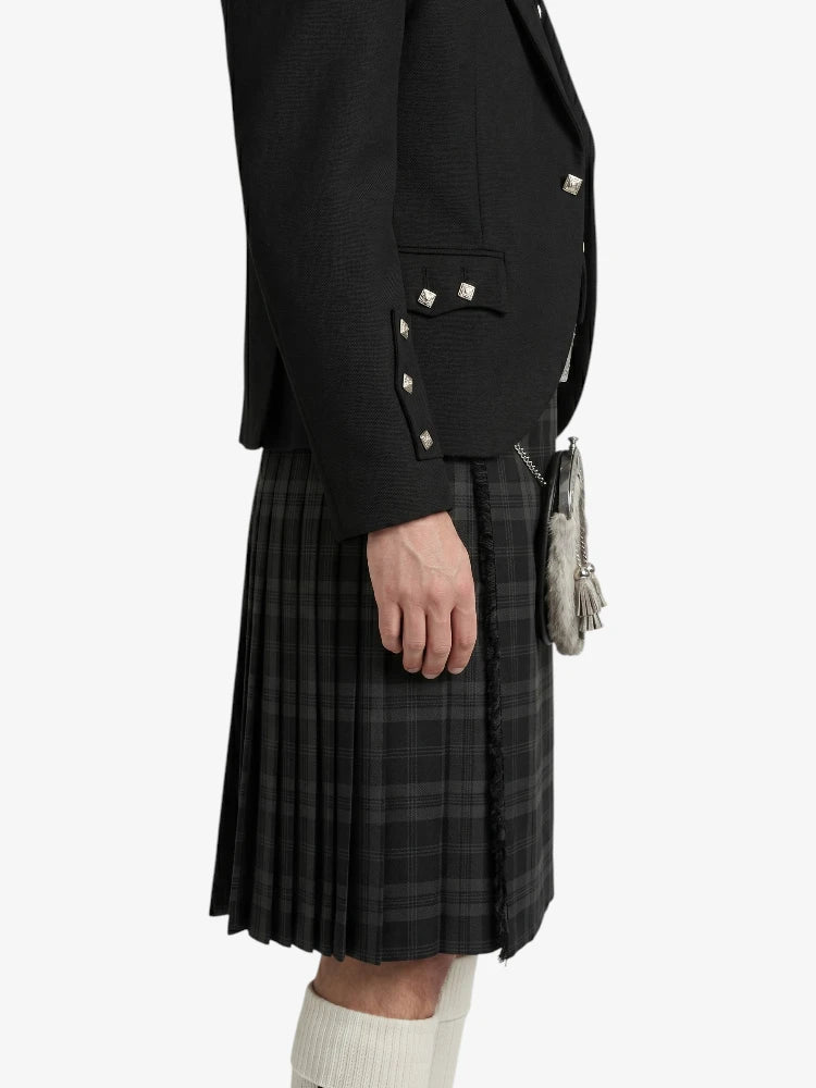 Person wearing a black jacket and plaid kilt on a white background