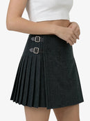 Black pleated skirt with silver buckles worn by a person on a white background