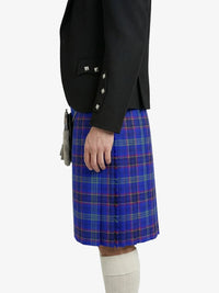 Person wearing a black blazer and blue plaid kilt on a white background