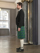Man wearing a black jacket and green plaid kilt in an elegant interior setting.