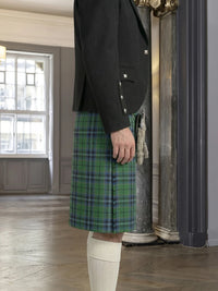 Person wearing a green plaid kilt with a black jacket in an indoor setting.