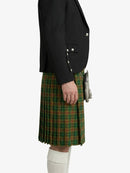 Person wearing a black blazer and green plaid kilt on a white background