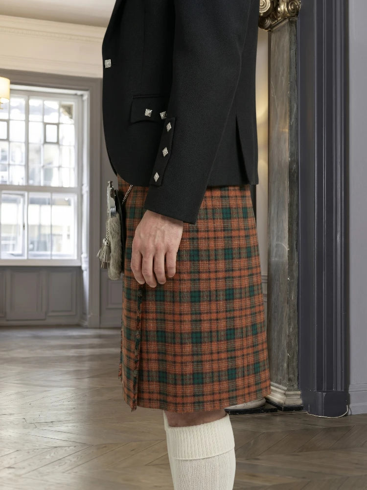 Person wearing a black jacket and plaid kilt indoors.
