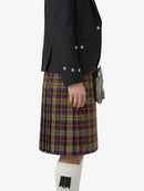 Person wearing a black jacket and plaid kilt on a white background