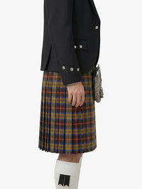 Person wearing a black jacket and plaid kilt on a white background