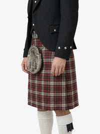 Person wearing a black jacket and red plaid kilt on a white background