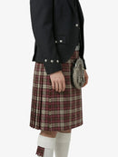 Person wearing a black jacket and red plaid kilt on a white background