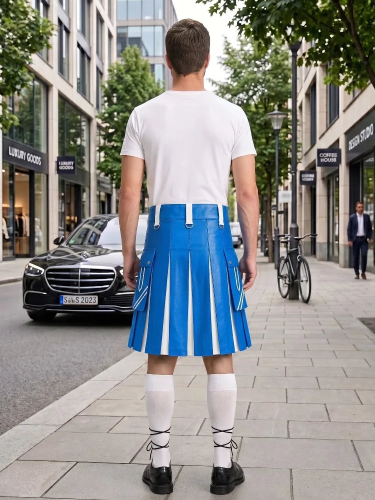 A man stands on a city sidewalk facing away from the camera, wearing a white T-shirt and a bright blue pleated kilt with white vertical stripes, white knee-high socks, and black shoes. Buildings, trees, a black car, and a bicycle are visible in the background.