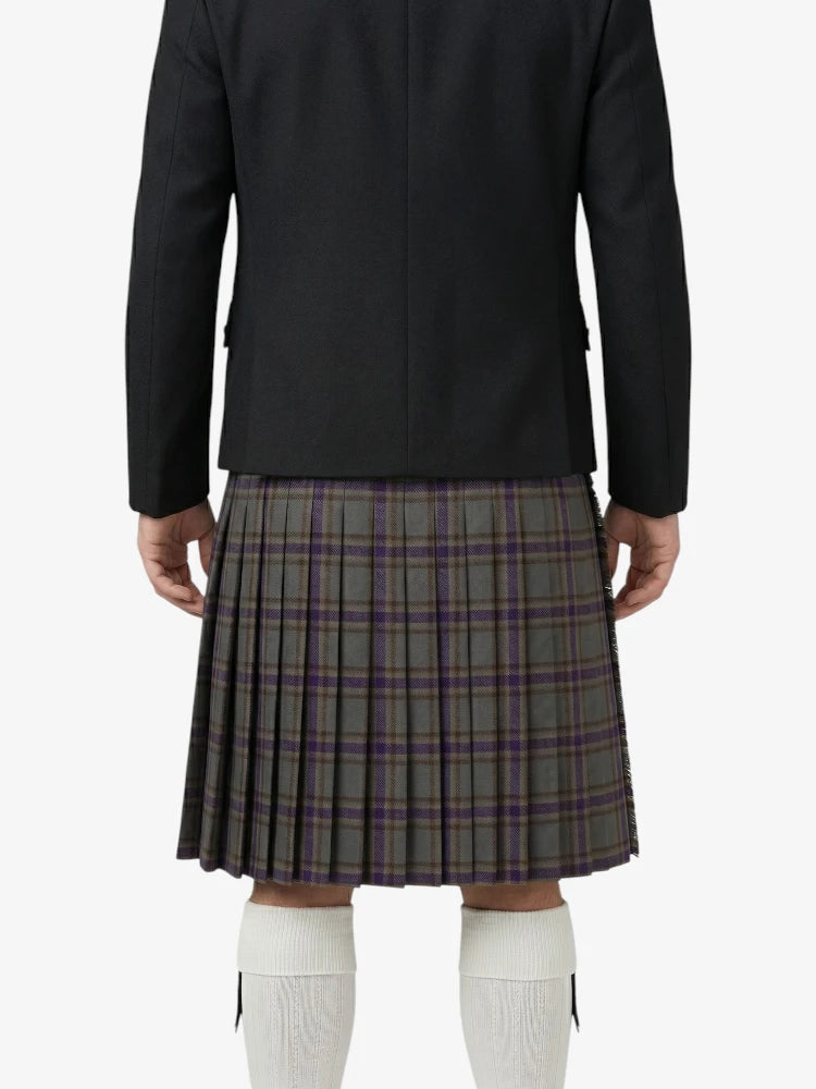 Person wearing a black jacket and plaid kilt on a white background