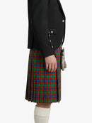 Person wearing a black blazer and a plaid kilt on a white background