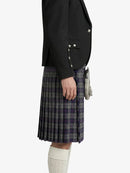 Person wearing a black blazer and plaid kilt on a white background