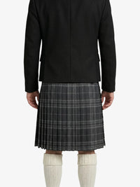 Person wearing a black jacket and plaid kilt on a white background