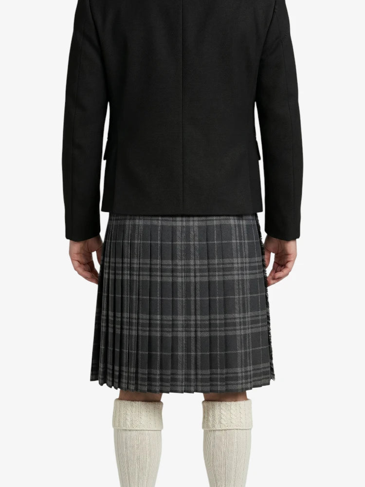 Person wearing a black jacket and plaid kilt on a white background