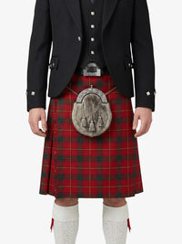 Person wearing a red tartan kilt with a black jacket and white socks on a white background