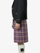 Person wearing a black jacket and purple plaid kilt on a white background