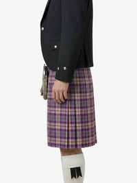 Person wearing a black jacket and purple plaid kilt on a white background
