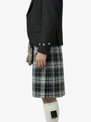 Person wearing a black blazer and plaid kilt on a white background