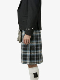 Person wearing a black blazer and plaid kilt on a white background