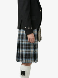 Person wearing a black jacket and plaid kilt on a white background