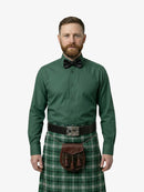 Man wearing a green shirt, bow tie, and plaid kilt on a white background