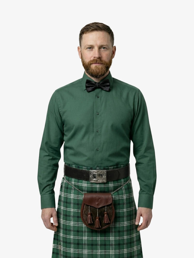 Man wearing a green shirt, bow tie, and plaid kilt on a white background