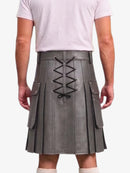 A person shown from the back wearing a gray pleated kilt with black lace-up detailing down the center and side flap pockets, paired with a light pink t-shirt and white socks against a plain white background.