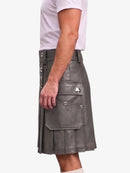 A man wearing a gray faux-leather kilt with silver-tone metal hardware, shown from the side against a plain white background.