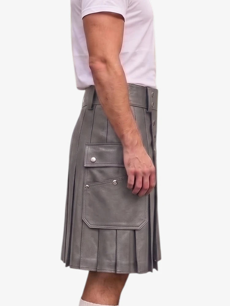 A side view of a person wearing a gray faux-leather kilt with pleats, flap pockets, and silver snap buttons, paired with a white t-shirt against a plain white background.