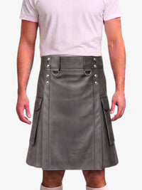 A man wearing a gray faux-leather kilt with silver-tone metal hardware, side pockets, and a belt loop, paired with a light pink t-shirt against a plain white background.