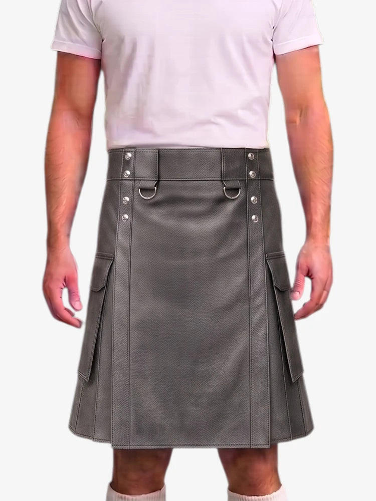 A man wearing a gray faux-leather kilt with silver-tone metal hardware, side pockets, and a belt loop, paired with a light pink t-shirt against a plain white background.