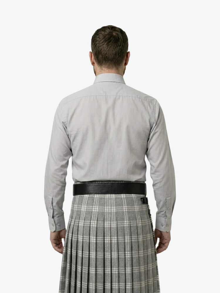 Man wearing a light gray shirt and plaid kilt on a white background
