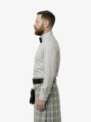 Man wearing a light gray shirt and plaid kilt on a white background