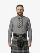 Man wearing a traditional Scottish kilt and shirt with a white background