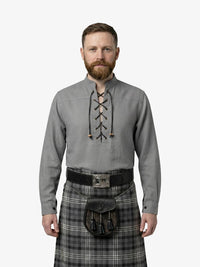 Man wearing a traditional Scottish kilt and shirt with a white background