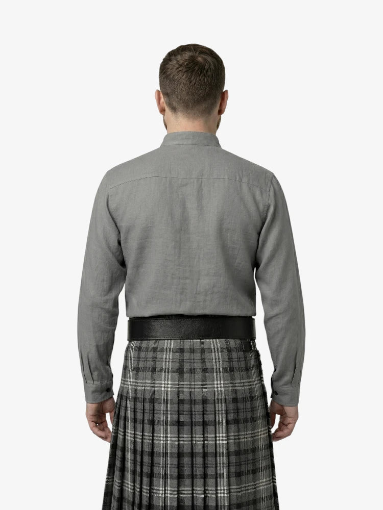 Man wearing a gray shirt and plaid kilt on a white background