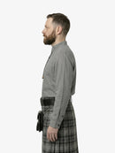 Man wearing a gray shirt and plaid kilt on a white background