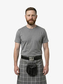 Man wearing a gray t-shirt and gray plaid kilt on a white background