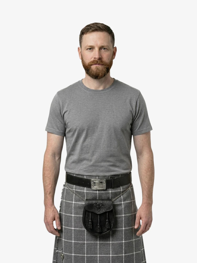 Man wearing a gray t-shirt and gray plaid kilt on a white background