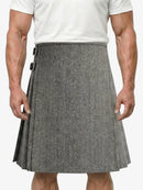 Person wearing a gray herringbone kilt on a white background