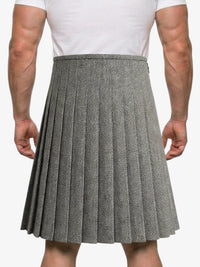 Person wearing a gray pleated skirt with a white shirt on a plain background