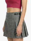 Person wearing a gray pleated skirt with a black belt on a white background