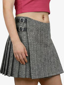 Person wearing a gray pleated skirt with black buckles on a white background