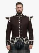 Man wearing a dark brown jacket with white trim and a grey watch tartan plaid kilt on a white background